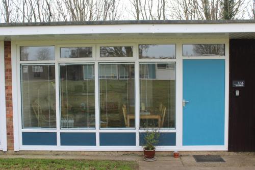 a screened in porch with a blue door at Stonesthrow 184 Broadside Chalet Park Stalham in Stalham