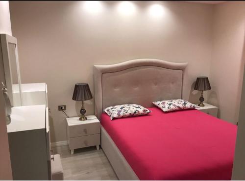 um quarto com uma cama rosa com duas almofadas em Arbana’s em Tirana
