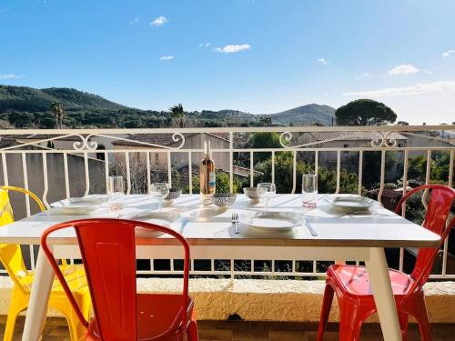 d'une table blanche avec des chaises rouges sur un balcon. dans l'établissement Cosy Appartement, Proche mer, à Saint-Cyr-sur-Mer