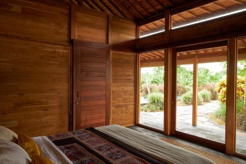 a bedroom with wooden walls and a large window at July Villas in Canggu