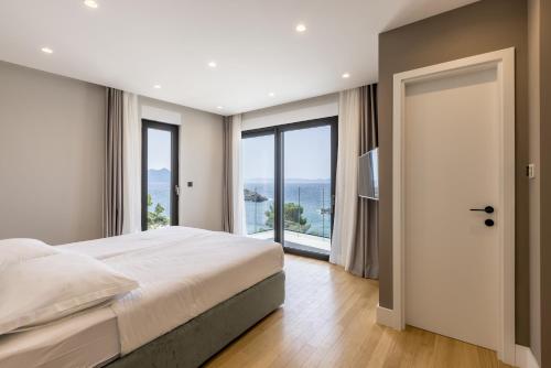 a bedroom with a large bed and large windows at Villa Luce Pelješac in Potomje
