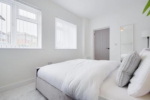 a white bedroom with a white bed and windows at Apartment 1 Castle Lane in Bournemouth