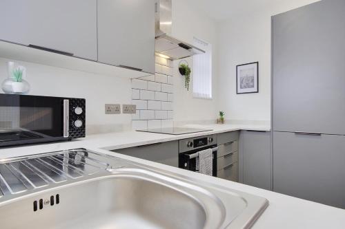 a white kitchen with a sink and a microwave at Apartment 1 Castle Lane in Bournemouth