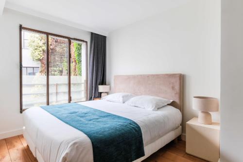 sypialnia z dużym łóżkiem i dużym oknem w obiekcie Chic duplex loft in trendy Bastille w Paryżu