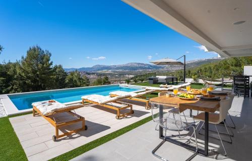 a patio with a table and chairs and a pool at Villa Sunset Split overviewing Split and Podstrana bay in Strožanac