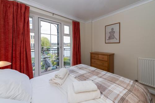 um quarto com uma cama e uma grande janela em Large Tranquil Riverside Flat with Thames Views - Pass the Keys em Reading