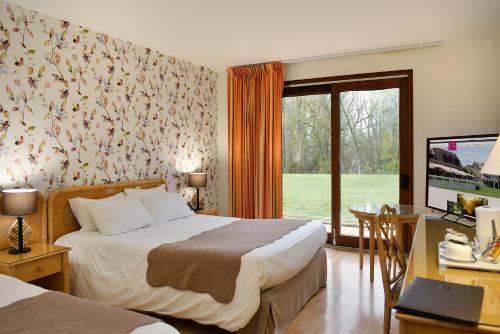 a bedroom with a bed and a desk with a computer at Logis Le Relais De Pouilly in Pouilly-sur-Loire