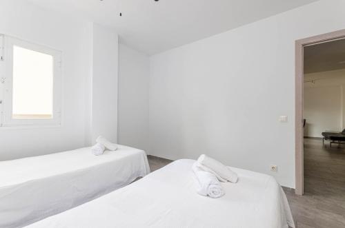 a white room with two beds and a window at Acapulco Apartments in Can Picafort