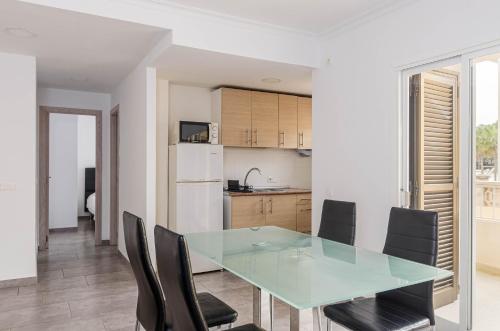 a kitchen and dining room with a glass table and chairs at Acapulco Apartments in Can Picafort