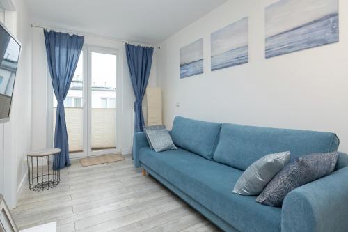 a blue couch in a living room with a window at Apartamenty "Bałtyk" Armii Krajowej w Świnoujściu by Renters in Świnoujście