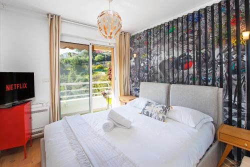 um quarto com uma cama branca e uma janela em Spacieux appartement - Parking privé & Piscine em Beausoleil