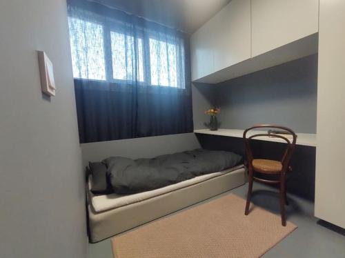 1 dormitorio con 1 cama, 1 silla y 1 ventana en Sjarmerende, sentrumsnær leilighet en Stavanger