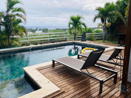 una piscina con 2 sillas en una terraza de madera en Villa vue mer avec Piscine - Au Rayon vert, en Saint-Paul