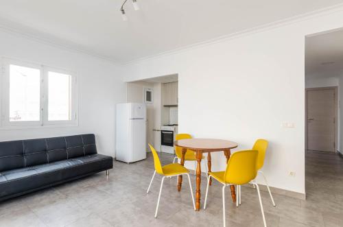 a living room with a table and yellow chairs at Acapulco Apartments in Can Picafort