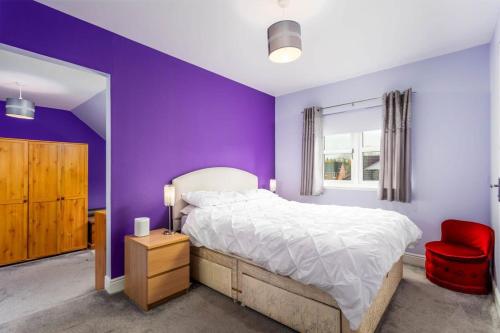 a purple bedroom with a bed and a red chair at 45 Doonvale Drive in Ayr