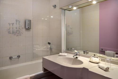 La salle de bains est pourvue d'un lavabo, d'une baignoire et d'un miroir. dans l'établissement Logis Le Relais De Pouilly, à Pouilly-sur-Loire