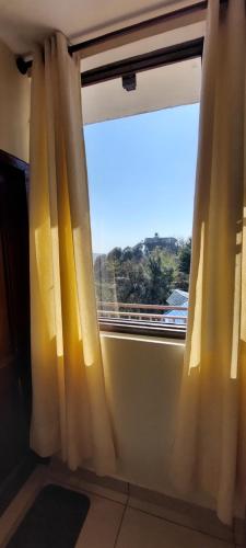 una ventana con cortinas amarillas en una habitación en Mountain Villa Mcleodganj, en Kangra