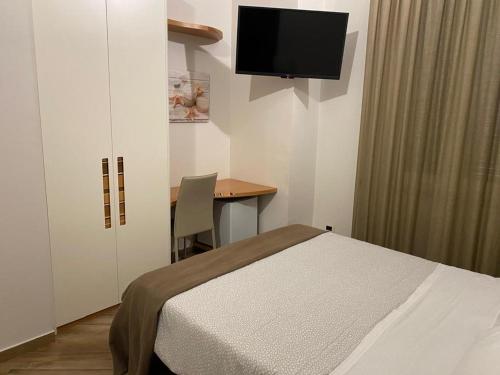 um quarto com uma cama e uma secretária com uma televisão em A 4 PASSI em Reggio di Calabria