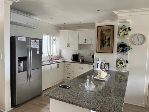 a kitchen with a stainless steel refrigerator and white cabinets at The Estuary Country Estate, Villa "Once Upon A Tide" in Port Edward