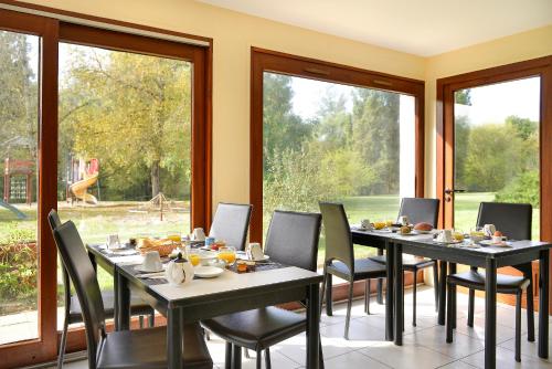 Un comedor con mesas y sillas y ventanas. en Hôtel Restaurant Le Relais De Pouilly, en Pouilly-sur-Loire