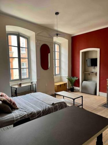 1 dormitorio con cama y pared roja en Chez Bouch, en Montauban