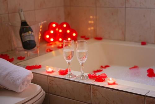 uma casa de banho com 2 copos de champanhe e uma banheira com velas em Hotel Cabanas Alto Da Serra em Canela