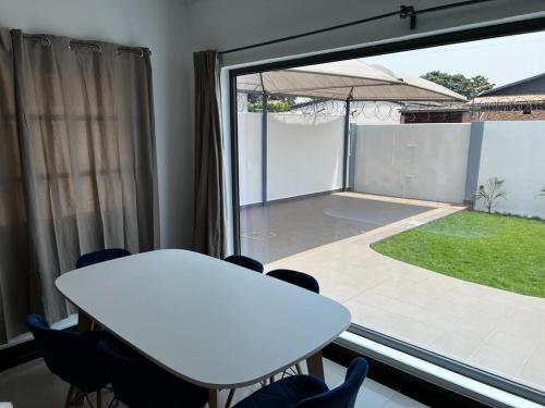 una mesa y sillas blancas en una habitación con una ventana grande en Villa Meublée Cité Arconville 10min d'EREVAN CALAVI en Abomey-Calavi