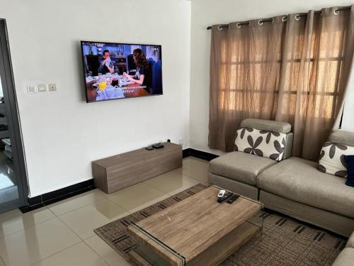 sala de estar con sofá y TV en la pared en Villa Meublée Cité Arconville 10min d'EREVAN CALAVI en Abomey-Calavi