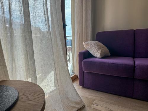 a purple couch in a living room with a window at Vivi Suites&Spa Molveno in Molveno