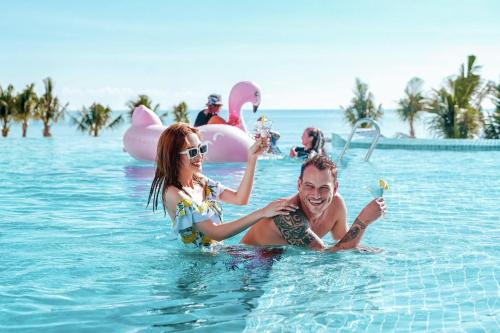 a man and woman playing in the water at a resort at The Oceanfront Apartment At Cam Ranh in Cam Ranh