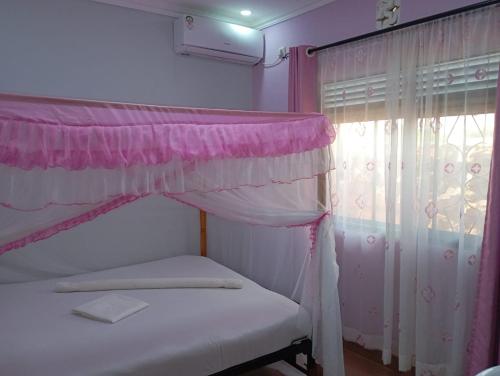 Quanam Woods Hotel في لودوار: غرفة نوم بسرير مع مظلة ونافذة