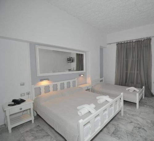 a bedroom with two beds and a mirror on the wall at Porto Castello in Fira