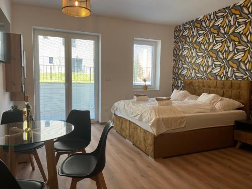 een slaapkamer met een bed en een tafel en stoelen bij Luxusní Apartmán NMNM Essence in Nové Město na Moravě