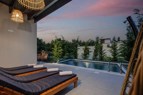een patio met 2 bedden en een zwembad bij Villa Medellin in Pridraga