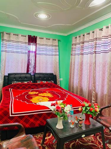a bedroom with a red bed with flowers on a table at Fab Ocean Guest House in Tangmarg
