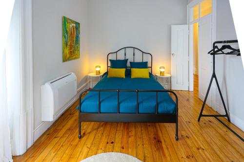 Gouveia Vintage House في غويفيا: غرفة نوم بسرير ذو شراشف زرقاء ومخدات صفراء
