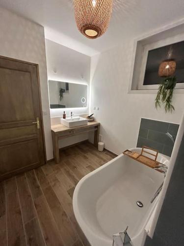 La salle de bains est pourvue d'une grande baignoire et d'un lavabo. dans l'établissement Chez Balthazar, à Elnes