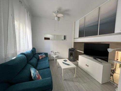 a living room with a blue couch and a tv at CASA EN ISLA DE TABARCA (ZONA PUERTO VIEJO) in Tabarca