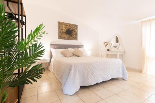 a white bedroom with a bed and a plant at Wish Apartment - Catania Centro Storico in Catania