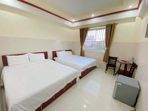 um quarto de hotel com duas camas e uma televisão em Tường Vi Motel em Hà Tiên