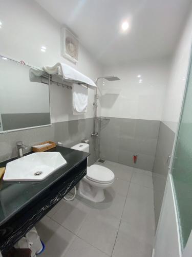 a bathroom with a sink and a toilet and a mirror at Tường Vi Motel in Hà Tiên