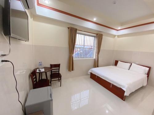 a bedroom with a bed and a table and a television at Tường Vi Motel in Hà Tiên