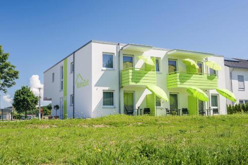 a white building with green balconies on top of a field at Apartments Amtzell, Selbst-Check-in in Amtzell