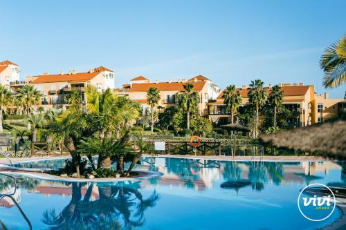 einen Pool in einem Resort mit Palmen und Gebäuden in der Unterkunft ViVi Homes - Casa Duque Pool, Terrace & Golf in Alhaurín de la Torre