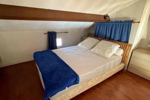 Dormitorio pequeño con cama con cortina azul en T1 bis vue mer 4 personnes piscine ouvert toute l année, en Bandol