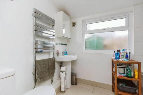 a white bathroom with a sink and a window at Affordable and comfort apartment in Ibadan