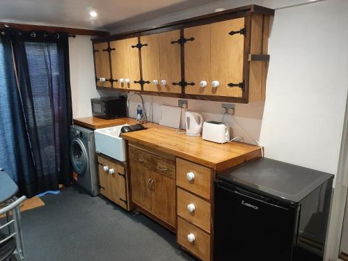 cocina con armarios de madera, lavadora y secadora en Mildenhall Suffolk en Mildenhall