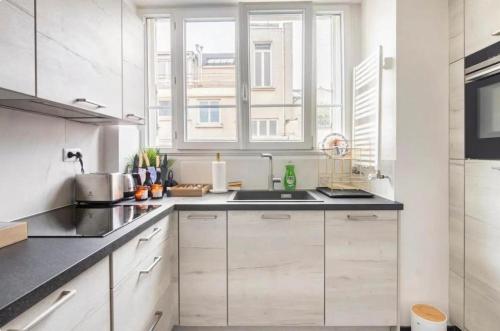 a white kitchen with white cabinets and a sink at Spacious Moderne & Design appartement 16em Arrondissement in Paris