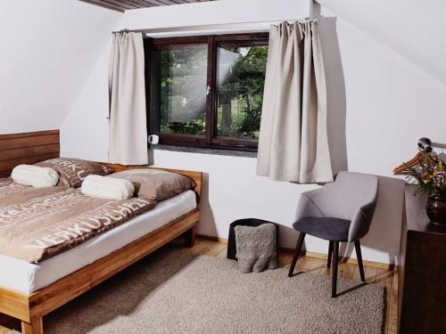a bedroom with a bed and a chair and a window at Drebach Modern retreat in Drebach