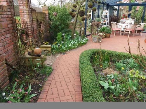 a garden with a brick walkway with plants and a table at Dollhouse Modern retreat in Wiesmoor